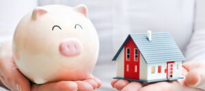 Save Money by performing Home Care. A piggybank in one hand and a home in the other.